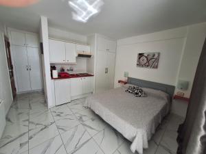 een slaapkamer met een bed en een keuken met witte kasten bij Ponderosa Holiday Studio 701 in Playa de las Americas