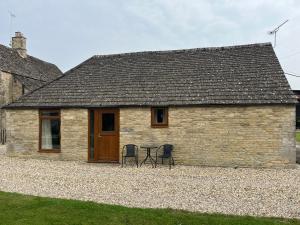 a building with two chairs and a table in front of it at Tupenny Cottage, Old Mill Farm, Cotswold Water Park in Cirencester