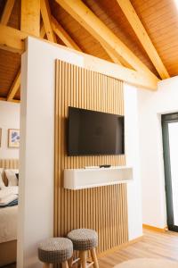 a living room with a tv and two stools at Alvarenga Apartments in Alvarenga