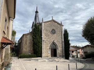 an old stone church with a clock tower at Les Galamières in Meximieux +4 photos