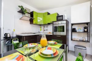 a kitchen with a dining table with green cabinets at Tram Sotto Casa - In DUOMO in un attimo in Milan