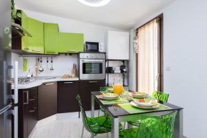 a kitchen with green cabinets and a table with chairs at Tram Sotto Casa - In DUOMO in un attimo in Milan