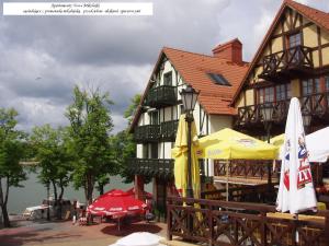 a large building with tables and umbrellas in front of it at Apartamenty Nowe Mikołajki in Mikołajki