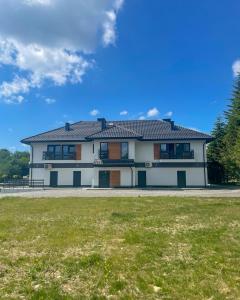a large white house with a grass field at Apartamenty Olszynka in Górki Wielkie