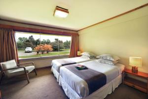 Habitación de hotel con cama grande y ventana en Hotel Naguilan, en Valdivia