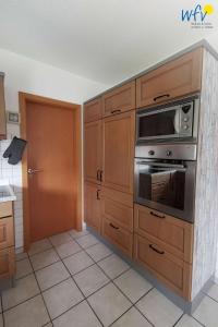 a kitchen with wooden cabinets and a microwave at Huus 24 in Borkum