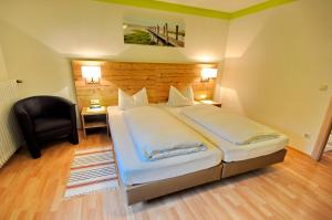 ein Schlafzimmer mit einem großen Bett und einem schwarzen Stuhl in der Unterkunft Wildkräuter-Gasthof Linde in Löffingen