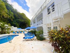 a hotel with chairs and a swimming pool next to a building at Mullins Beach Houses in Saint Peter