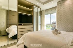 a bedroom with a bed with a tv and a window at Sophisticated fit with 3 suites Jurere LES403 in Florianópolis