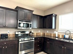 cocina con armarios de madera oscura y microondas en Spacious Family Retreat with Hot Tub & Home Theater, en Meridian