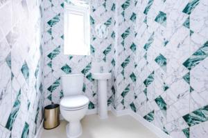 e bagno con servizi igienici bianchi e piastrelle verdi e bianche. di Spacious 4-Bed Manchester Home a Manchester
