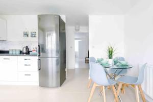 una cucina con tavolo e frigorifero in acciaio inox di Spacious 4-Bed Manchester Home a Manchester