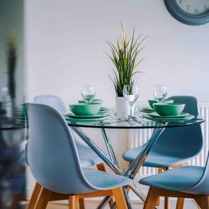 un tavolo di vetro con sedie, piatti e bicchieri da vino di Spacious 4-Bed Manchester Home a Manchester Altre 20 foto