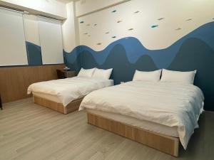 2 letti in una camera con un murale di 洄游民宿 Migration B&B a Donggang