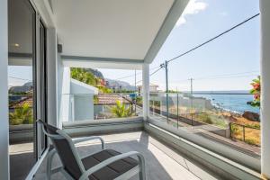 a balcony with a chair and a view of the ocean at Coastal Charm by Homie in Quinta do Almeida