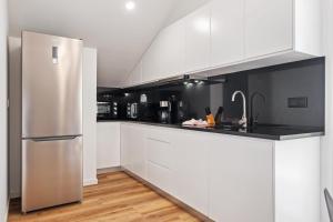 a kitchen with white cabinets and a stainless steel refrigerator at Coastal Charm by Homie in Quinta do Almeida +79 photos