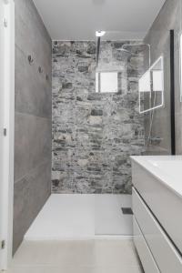 a bathroom with a stone wall and a shower at Modern Sea View Apartment Near Beach & Pool Puerto Rico in Puerto Rico de Gran Canaria +28 photos