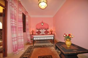 Habitación con cama, mesa y jarrón de flores en Riad La Famille, en Marrakech