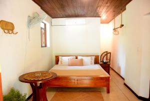 a bedroom with a bed and a table at Rasara Home Stay in Ahangama