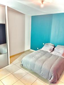 a bed in a room with a blue wall at room in house in Villefontaine