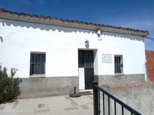 a white building with a black door and windows at La casita en la Alcornocosa -Sevilla in Seville