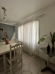 une salle à manger avec une table et un rideau blanc dans l'établissement Casa Charmosa Centro Balneário Camboriú, à Balneário Camboriú