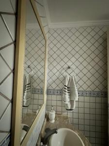 une salle de bain avec un lavabo, un miroir et des serviettes dans l'établissement Casa Charmosa Centro Balneário Camboriú, à Balneário Camboriú