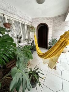 un hamac jaune dans une pièce avec des plantes dans l'établissement Casa Charmosa Centro Balneário Camboriú, à Balneário Camboriú