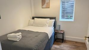 a small bedroom with a bed with white sheets and a window at 4Bedroom house at Town Centre with Free Driveway Parking in Buckinghamshire