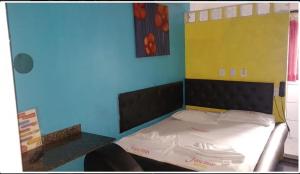 a bedroom with a bed with a yellow and blue wall at Hotel Fascinio-Adults Only in Salvador
