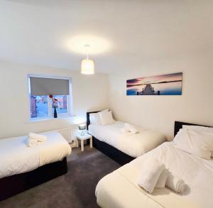 a room with three beds and a window at Luxury Family Retreat Near Alton Towers - Free Parking & Garden in Stoke on Trent