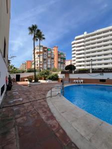 a swimming pool in front of a large building at CT 301 - Faro's Fuengirola Centro Studio in Fuengirola