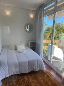 a white bedroom with a bed and a large window at Discovery Apartment with patio Discovery 2 in Machico