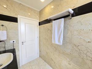 Eli's Seafront Apartment في سارنده: حمام مع حوض ومنشفة بيضاء +28 صورة