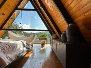 a bedroom with a bed and a large window at Cabanas Araucária in Campos do Jordão