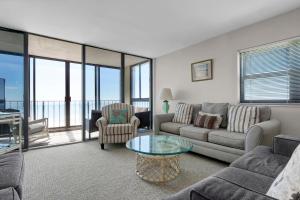 uma sala de estar com um sofá e uma mesa de vidro em The Islander - 6F by Sea Scape Properties em Wrightsville Beach
