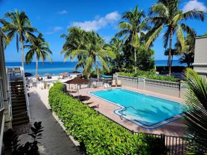 a swimming pool with palm trees and the ocean at Vanderbilt Beach Resort in Naples