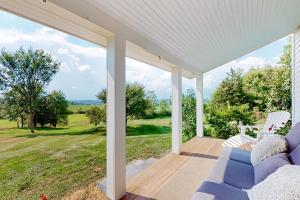 a porch with a blue couch and a view of a field at Cider Hill Haven in New Haven