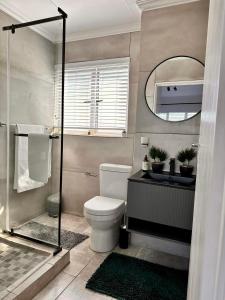 a bathroom with a toilet and a sink and a mirror at West Beach Luxury Apartment in Bloubergstrand