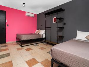 a room with two beds and a pink wall at Adhoc Cintermex in Monterrey