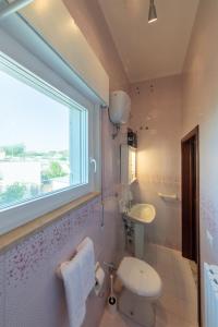 Un baño con inodoro, lavabo y ventana. en Villa Eucalipti sul mare, en Bari