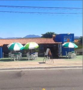 a group of tables and chairs with umbrellas on a sidewalk at SCR-Saquarema-Pousada da Tia Lúcia à Beira Mar in Saquarema