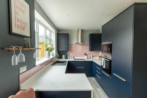 a kitchen with blue cabinets and a white counter at HIGHBANK HOUSE - Three Bed Stylish House in North Yorkshire in Harrogate