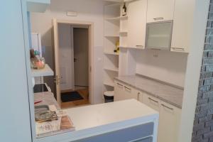 a kitchen with white cabinets and a white counter top at Apartmani Stanković in Vranje