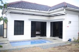 a white house with a swimming pool in front of it at Villa indah in Beber