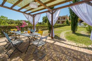 a patio with a table and chairs under a pergola at Holiday home with panoramic view of the forest in Polykhrono