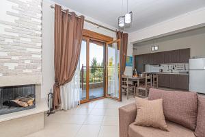 a living room with a fireplace and a kitchen at Holiday home with panoramic view of the forest in Polykhrono