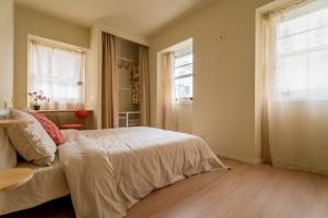 a bedroom with a bed and a table and two windows at Miña Nai Apartment in Ferrol
