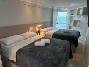 due letti in una stanza d'albergo con asciugamani sopra di 2704 Flat Beira Mar Av Boa viagem Vista Deslumbrante e com cozinha a Recife