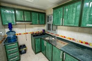 a green kitchen with green cabinets and a sink at tourist Peaceful Family Rooms Abu Dhabi ME11APT baith al jannah LLC in Abu Dhabi
